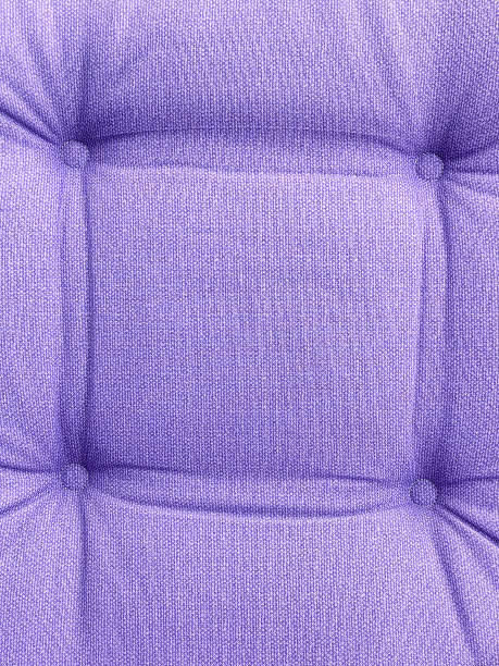 A vibrant purple sofa close-up with soft, tufted cushions. Space for copy.