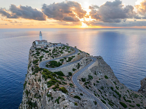 Scenic road to the Cap de Formentor lighthouse seen at sunrise, aerial picture. The road is one of the most scenic of Mallorca with stunning view above the coast.  Cap de Formentor peninsula, Sierra de Tramuntana, Pollenca, Mallorca, Balearic Islands, Mediterranean Sea, Spain