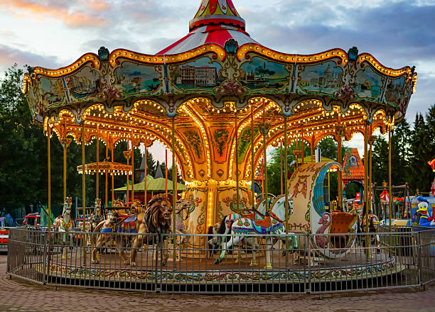 The graceful central column of a swing ride at a fair is lit by colorful lights at night.