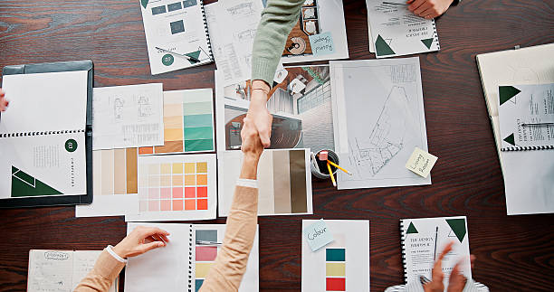 istock Interior designer, documents and shaking hands with partnership in office for renovation offer, deal and contract. Above, paperwork and people with handshake for design proposal approval or agreement 2236900443