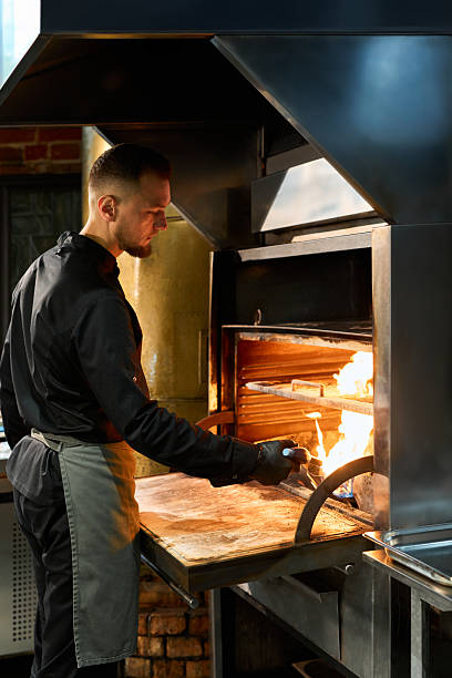 istock Adult Caucasian Man Using Blowtorch inside Fired Oven at Restaurant Kitchen 2236902542