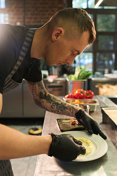 istock Young Adult Caucasian Man Decorating Dish While Working in Professional Kitchen 2236902546