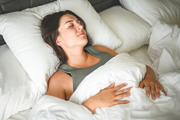 istock Beautiful young woman sleeping on a bed with white bed linen 2236902842