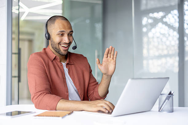 istock Support service worker with headset smiling, talking and consulting customers online remotely. Man working with laptop inside office 2236902884