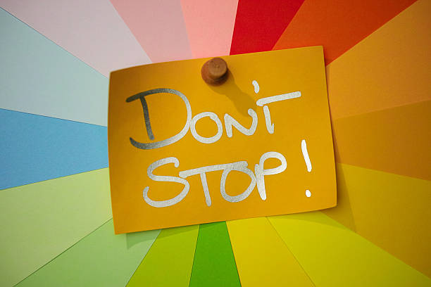 istock Yellow paper note pinned to a colorful array of different pastel rainbow colored note papers set in a circular spiral, with the inspirational words 'DON'T STOP!' written on it. 2236905831