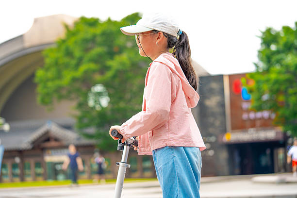 Asian girl is going to ride a scooter. Copy space. High quality photo