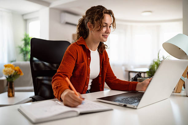 istock Young woman working on laptop at home in a bright interior setting 2236906195