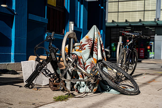 View of damaged bicycle with missing wheel locked on sidewalk in downtown.