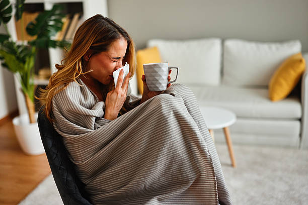 istock Woman sneezing into tissue having cold and flu at home 2236909378