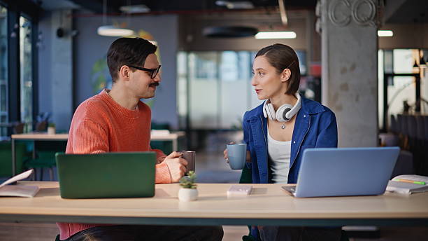 istock Relaxed team members drinking coffee at laptop workplace closeup. Two colleagues 2236909499