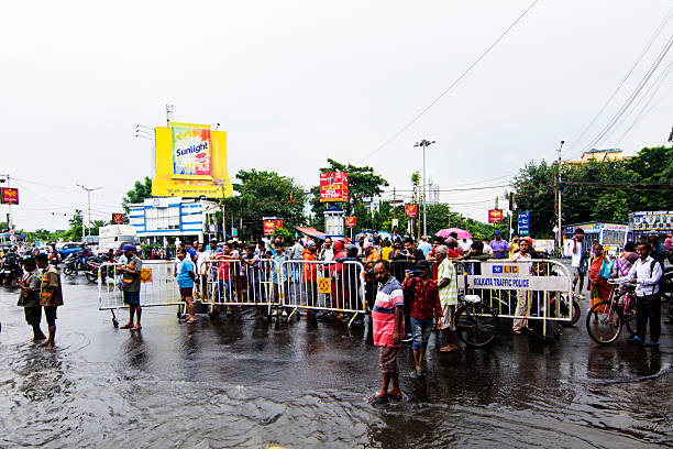 September, 23rd, 2025, Kolkata, India: People gather to witness a waterlogged road after overnight heavy rain, highlighting poor drainage, urban struggle, and community curiosity during monsoon flooding.