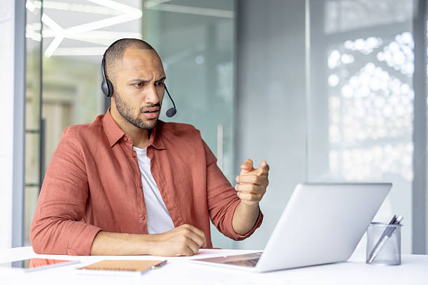 istock A frustrated man in a headset gestures while facing his laptop during a video conference call. 2236912462