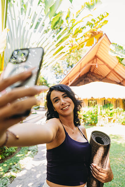 istock Woman taking selfie with yoga mat in tropical garden 2236914708