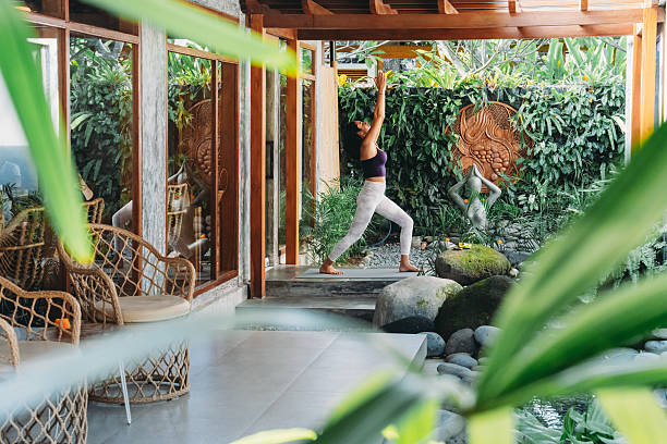 istock Woman practicing yoga warrior pose in tropical garden 2236914788