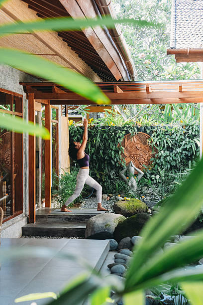 istock Woman doing yoga warrior pose in tropical garden 2236914794