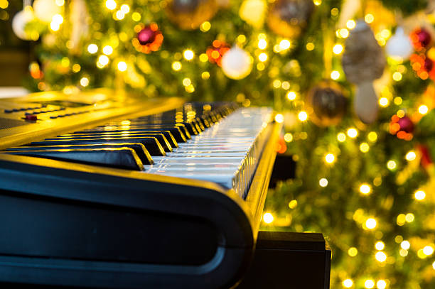 Piano next to a Christmas tree with selective focus on the keys