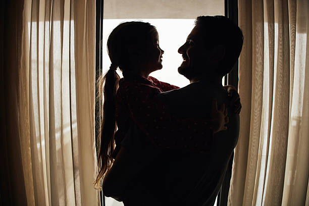 Beautiful girl and father bonding early in the morning by the window on an winter day.
