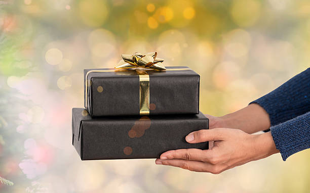 istock Hands holding elegant black gift boxes with golden ribbon bow festive celebration luxury present holiday surprise Christmas and special occasion concept 2236921734