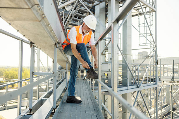 istock Senior Male Worker in Hard Hat Securing Boot on Elevated Industrial Platform 2236921925
