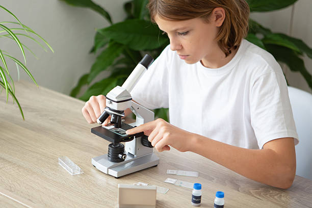 istock Girl studies biology at home using a microscope to examine plants during online school 2236922117