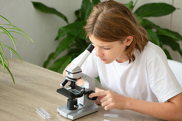 istock Girl studies biology at home using a microscope to examine plant samples during her online education 2236922135