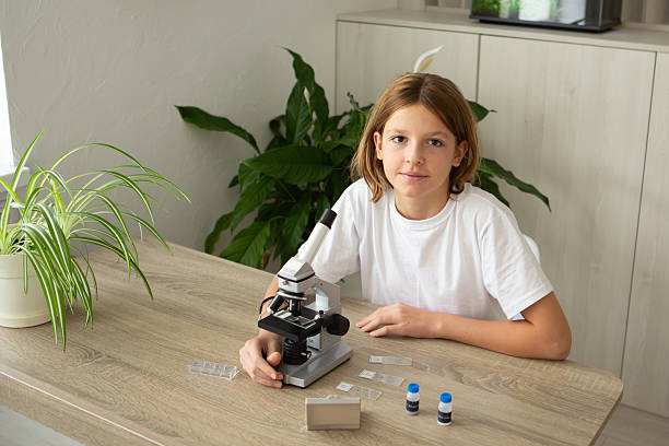 istock Girl studies biology at home while examining plants under a microscope during back-to-school time 2236922140