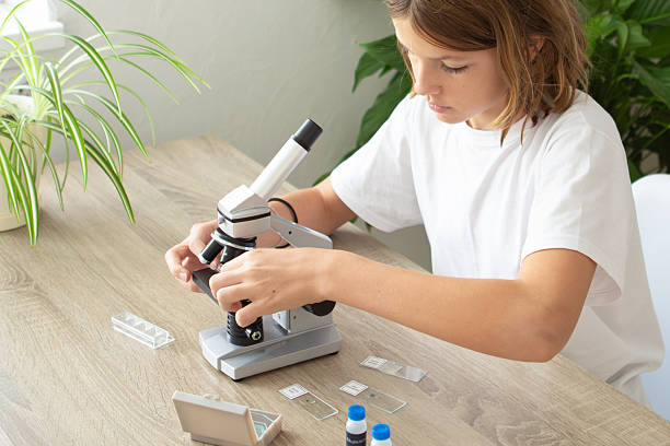 istock Girl studies biology at home while examining plants with a microscope during back-to-school season 2236922149