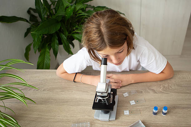 istock Girl studies biology at home using a microscope to examine plant samples for her online education 2236922157