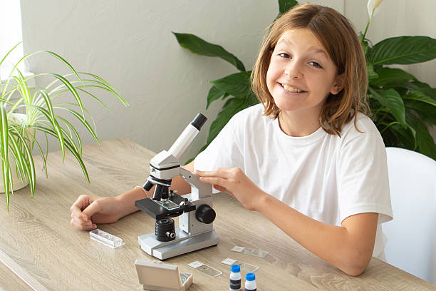 istock Girl studies biology at home, examining plants through a microscope while preparing for school 2236922162