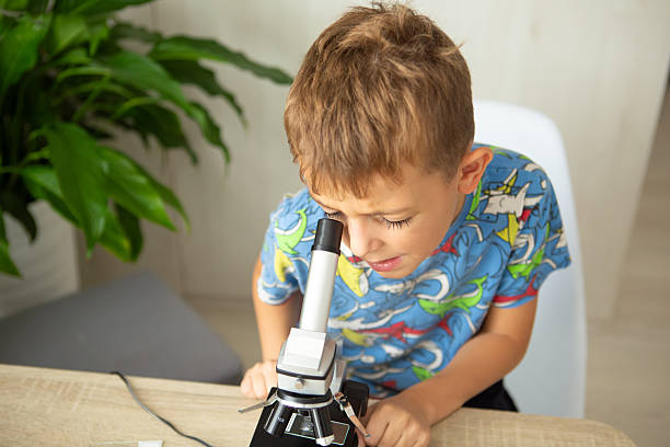 istock Young boy studies biology at home with microscope examining plants, embracing online education 2236922262