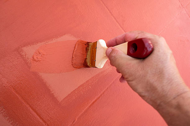 istock Painter applying tile-colored paint to the floor of a terrace 2236924339