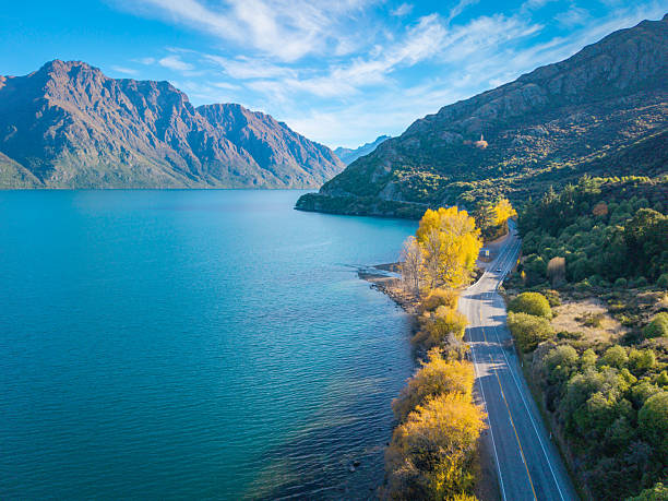 beautiful road trip route along  turquoise Wakatipu lake we can see colorful leave trees along this route South Island New Zealand