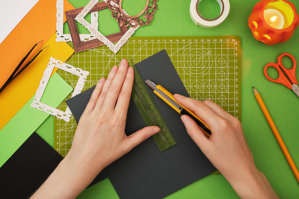 istock Making a Halloween craft. Hands cutting grey paper with a ruler and utility knife on a grid cutting mat 2236931801