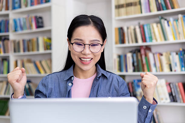 istock Excited woman celebrating success while working on laptop in library setting 2236931837