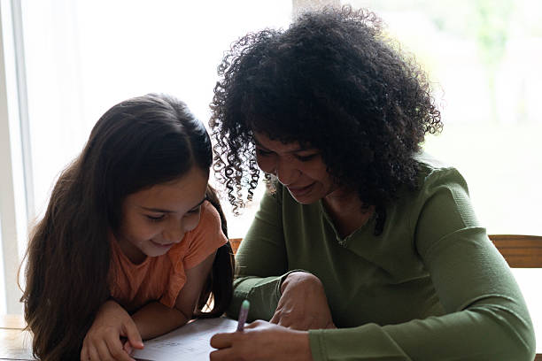 istock Caregiver helping girl doing homework 2236937878