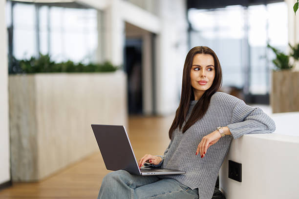 istock Young woman smiling while working with laptop in office 2236942574