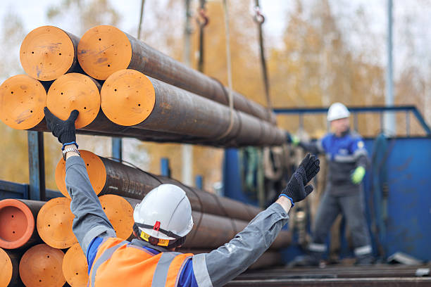 istock Construction Workers Handling Heavy Steel Pipes Outdoors 2236942789