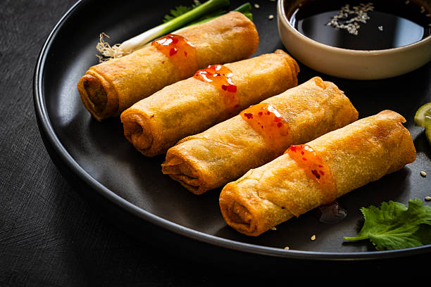 istock Spring rolls filled with meat and vegetables served with soy sauce on wooden table 2236942926