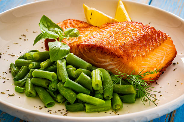 Seared salmon steak with boiled green bean on wooden table