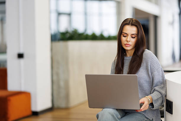 istock Young woman smiling while working with laptop in office 2236943007