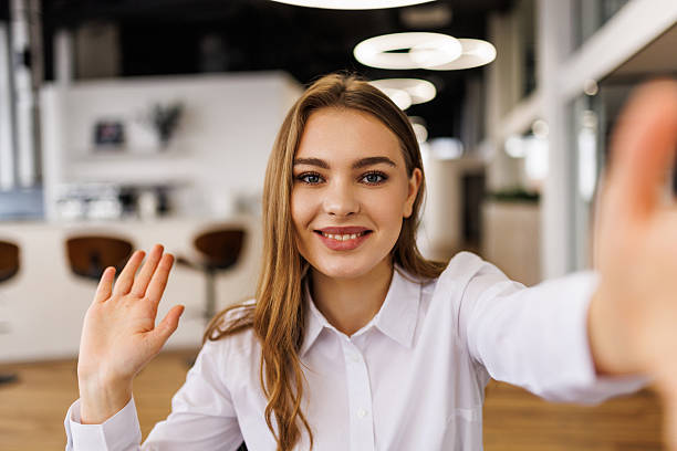 istock Smiling woman waving during video call in modern office. 2236948715