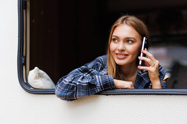istock Young woman talking phone while stand in front of motorhome 2236952947