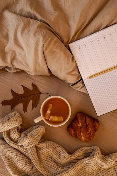 istock Cozy autumn scene with tea, croissant, and a notebook on a bed. 2236954001