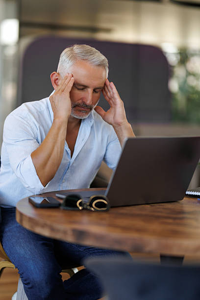 istock Stressed office worker sitting at desk with laptop feeling burnout. Man looking frustrated while working on laptop. 2236958240