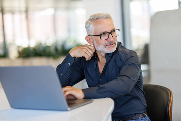 istock Mature male entrepreneur or executive sitting at work desk using laptop computer technology. 2236958414