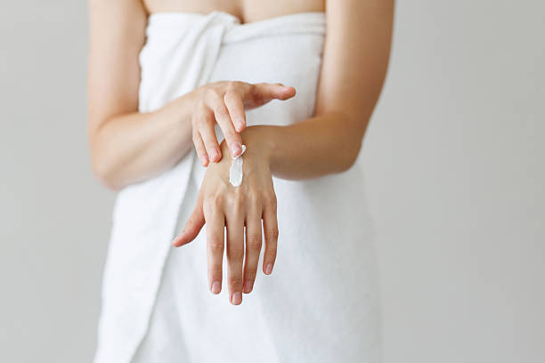 istock Young woman in spa bathrobe applying hand cream moisturizer on her hands for softing effect. Recreation, beauty treatment at home 2236965153
