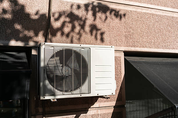 istock Air conditioner unit attached to building wall in sunlight. This image represents the concept of urban technology, ventilation, cooling, structure, and modern city life. 2236966225