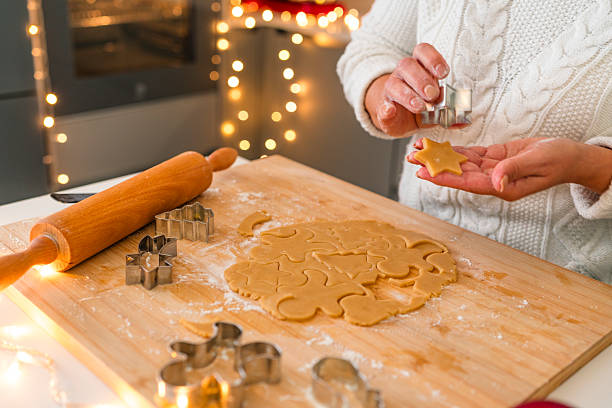 istock Unrecognizable woman making different shapes gingerbread cookies with cookie cutter in kitchen. Person preparing sweet food for Christmas Holidays at home. 2236974127