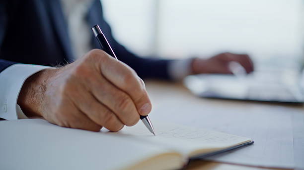 istock Lawyer hands writing notebook at office closeup. Gray-haired businessman working 2236976902