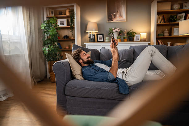 istock Happy man relaxing on couch using smartphone for social media 2236978735